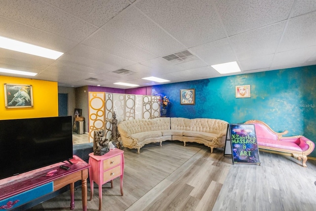 living room with a drop ceiling and wood-type flooring