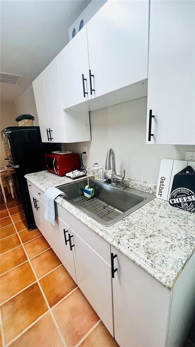 kitchen featuring light tile patterned flooring, white cabinetry, and sink