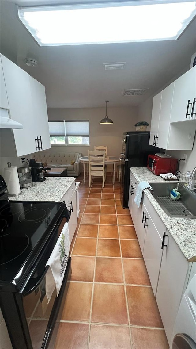 kitchen featuring black appliances, white cabinets, light tile patterned flooring, and decorative light fixtures