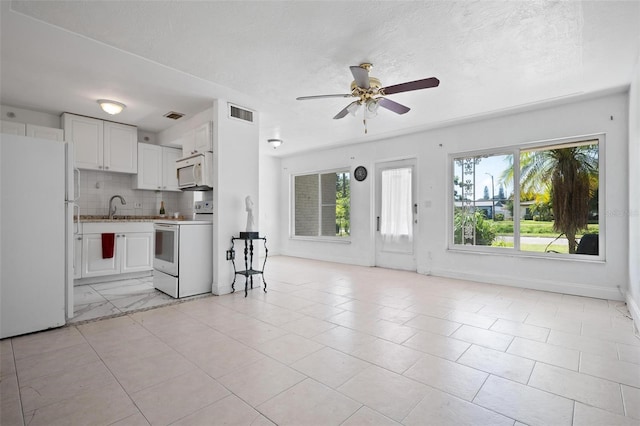 kitchen featuring white appliances, backsplash, ceiling fan, white cabinets, and light tile patterned flooring