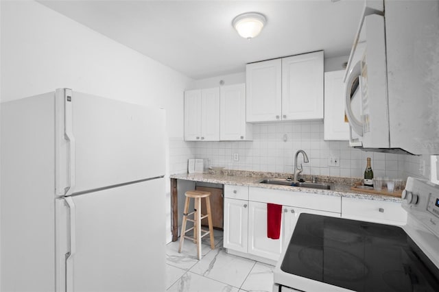 kitchen with white appliances, light stone counters, white cabinets, backsplash, and sink