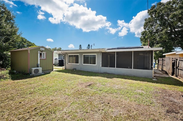 rear view of property featuring ac unit, a sunroom, and a lawn