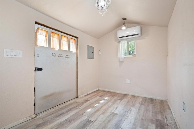 interior space featuring electric panel, light hardwood / wood-style flooring, a wall mounted air conditioner, and vaulted ceiling