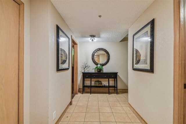 corridor with a textured ceiling and light tile patterned floors