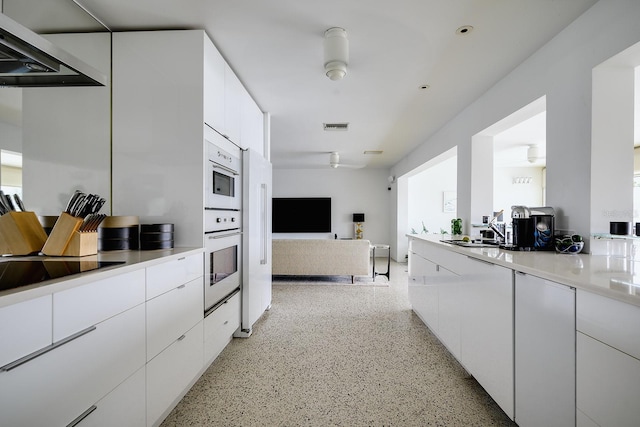 440 64th Ave, St Pete Beach, FL 33706 - kitchen featuring dark aggregate flooring, range hood, white cabinets, and modern cabinets