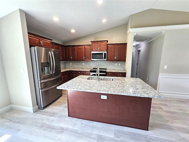 kitchen with vaulted ceiling, appliances with stainless steel finishes, a wainscoted wall, and a sink