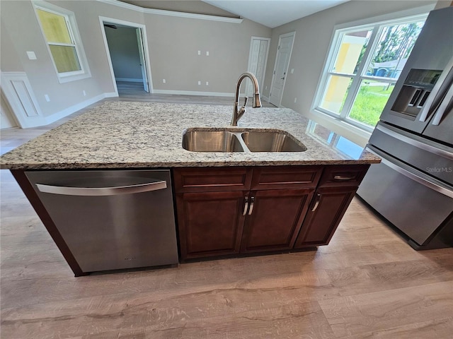 kitchen featuring lofted ceiling, light stone counters, a sink, dishwasher, and an island with sink