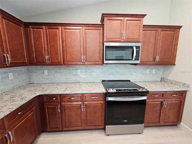 kitchen featuring tasteful backsplash, appliances with stainless steel finishes, vaulted ceiling, and light stone counters