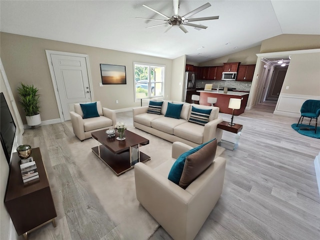 living room featuring light hardwood / wood-style floors, ceiling fan, and vaulted ceiling