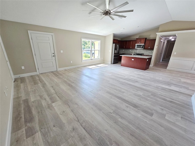 kitchen with stainless steel appliances, light wood-style flooring, a ceiling fan, open floor plan, and vaulted ceiling