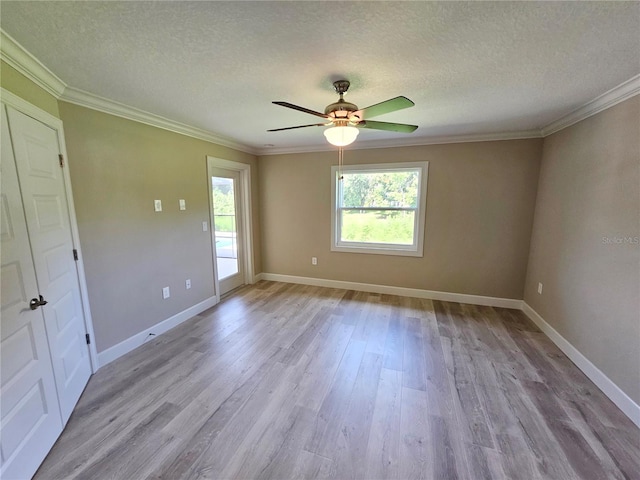 empty room with crown molding, a textured ceiling, baseboards, and wood finished floors