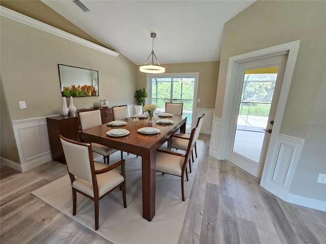 dining room featuring lofted ceiling, light wood finished floors, visible vents, and wainscoting