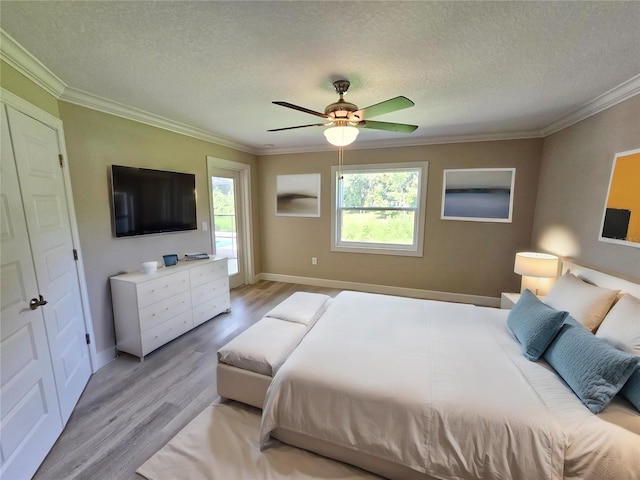 bedroom with a textured ceiling, ceiling fan, ornamental molding, and light wood-type flooring