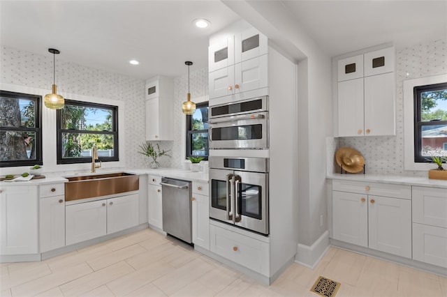 kitchen featuring white cabinetry, stainless steel appliances, and hanging light fixtures