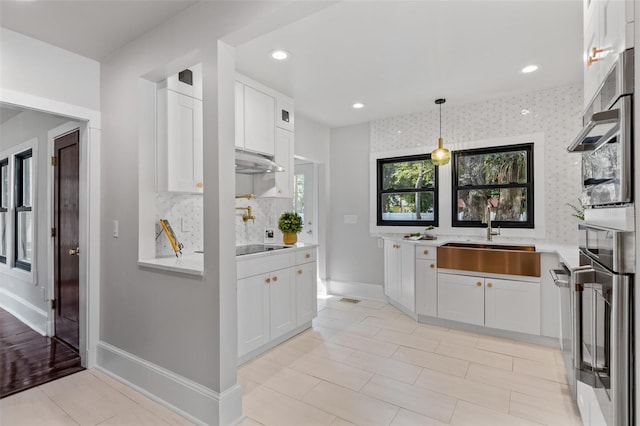 kitchen with sink, tasteful backsplash, hanging light fixtures, light tile patterned floors, and white cabinets