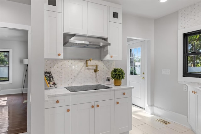 kitchen with black electric cooktop, white cabinetry, plenty of natural light, and exhaust hood