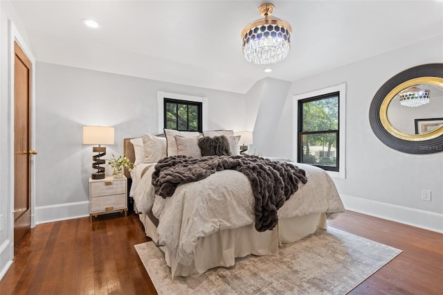 bedroom featuring multiple windows, a chandelier, and dark hardwood / wood-style flooring