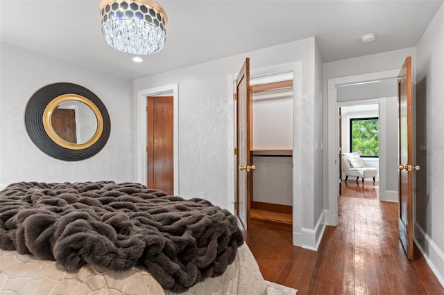 bedroom featuring dark wood-type flooring, an inviting chandelier, and a closet