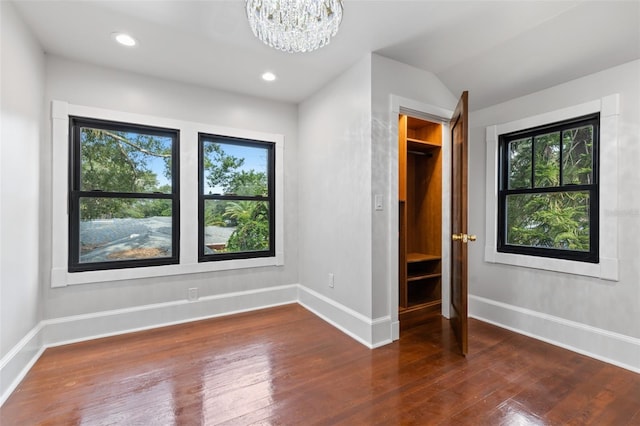 unfurnished bedroom featuring lofted ceiling, dark hardwood / wood-style floors, and a chandelier