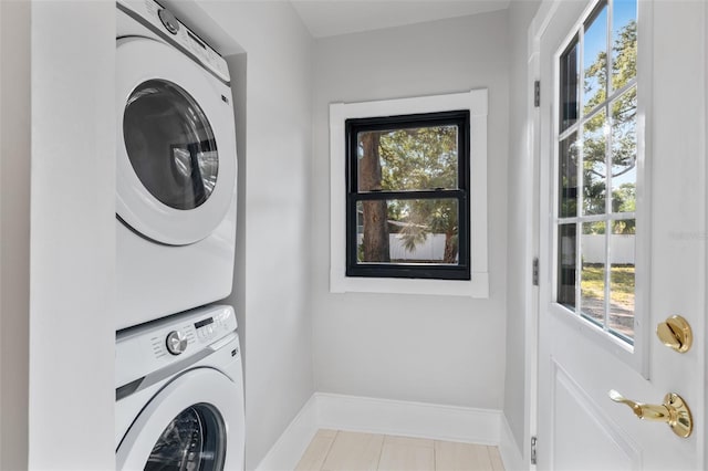 laundry room with stacked washer and dryer and light tile patterned floors