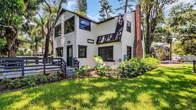 rear view of property featuring a yard and a deck