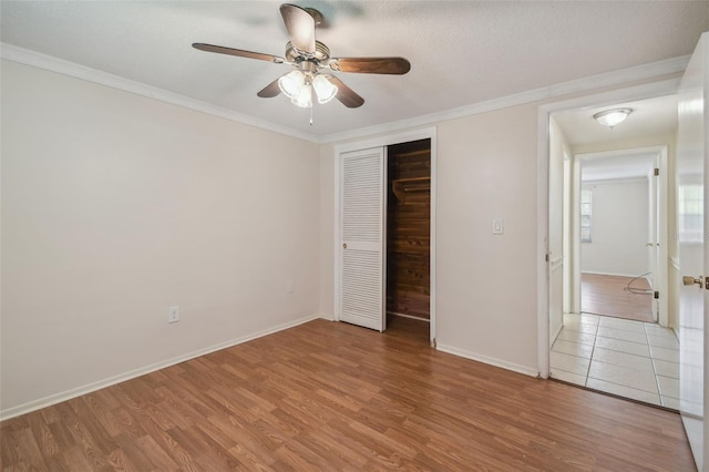 unfurnished bedroom featuring wood-type flooring, ornamental molding, a closet, and ceiling fan