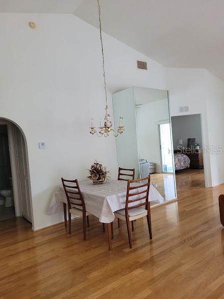 dining area with hardwood / wood-style flooring, an inviting chandelier, and lofted ceiling