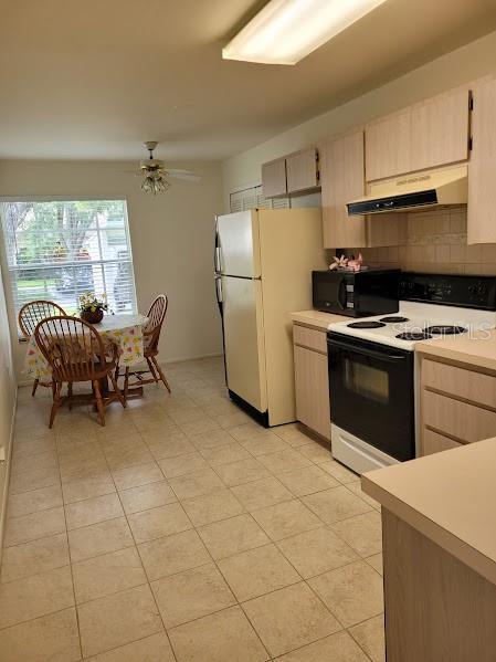 kitchen with ceiling fan, light brown cabinetry, light tile patterned floors, and white appliances