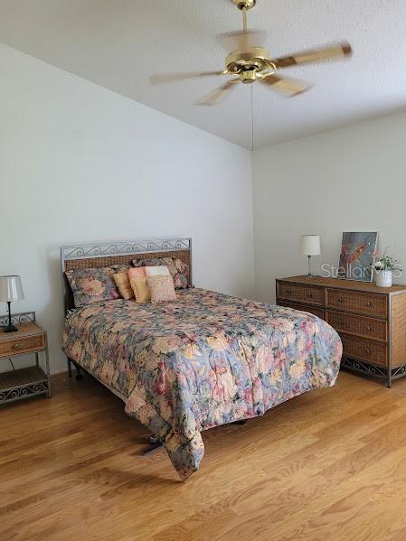 bedroom with ceiling fan, light wood-type flooring, and a textured ceiling