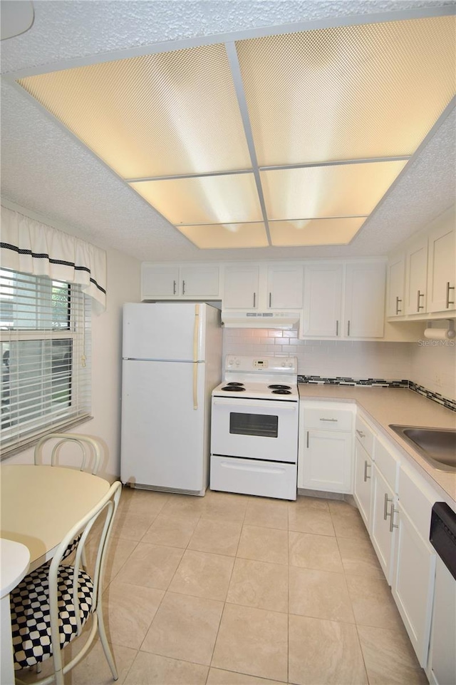 kitchen with white cabinets, white appliances, light tile patterned floors, and sink