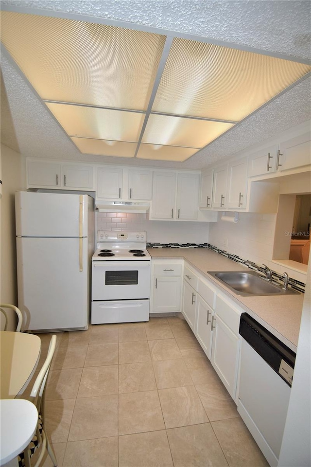 kitchen with sink, backsplash, white cabinetry, light tile patterned flooring, and white appliances