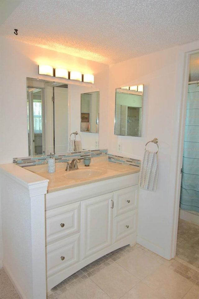 bathroom with a textured ceiling, vanity, and tile patterned flooring