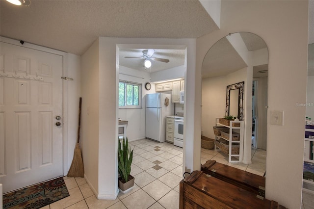 foyer entrance featuring ceiling fan, light tile patterned floors, and a textured ceiling