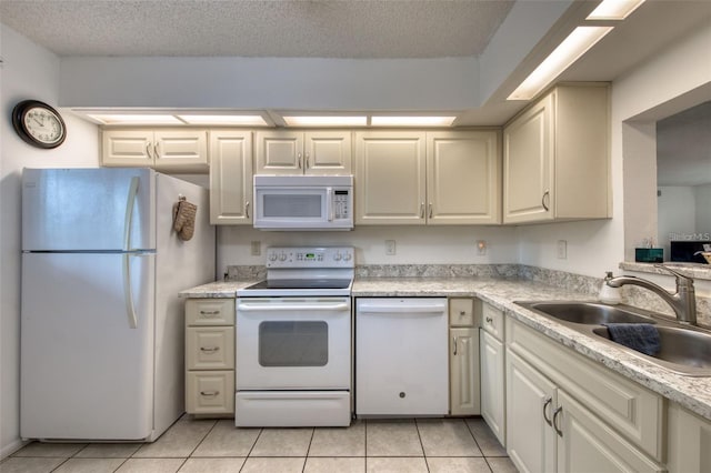 kitchen featuring sink, white appliances, light tile patterned floors, and a textured ceiling