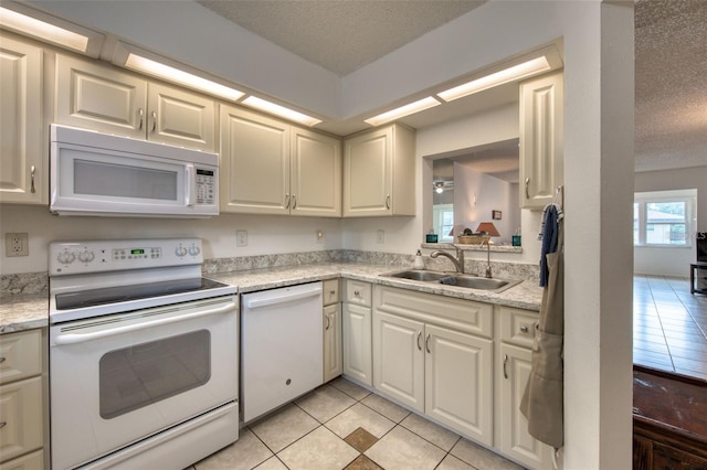 kitchen featuring sink, white appliances, light tile patterned floors, and a textured ceiling