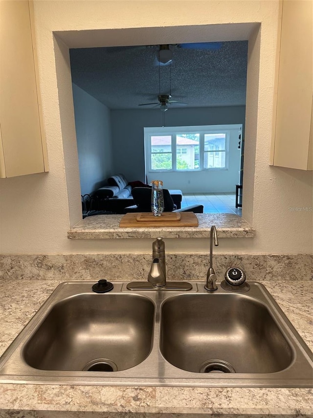 room details featuring ceiling fan, white cabinets, and sink