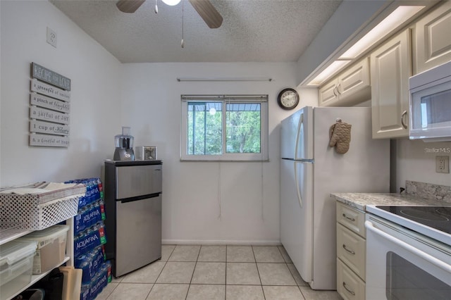 kitchen with a textured ceiling, ceiling fan, light tile patterned flooring, and white appliances