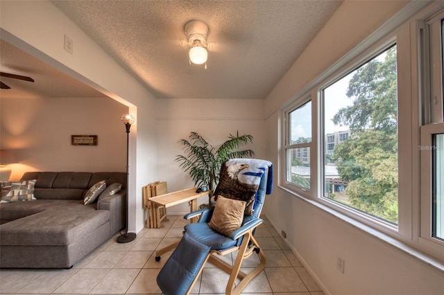 sitting room featuring a textured ceiling, ceiling fan, and light tile patterned flooring