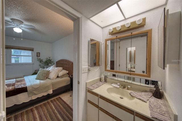 bathroom with ceiling fan, vanity, and a textured ceiling