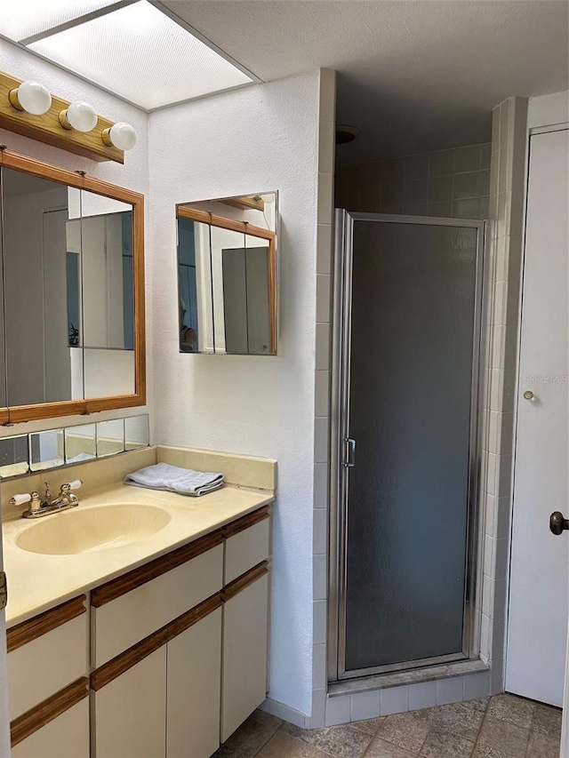 bathroom featuring a shower with shower door and vanity