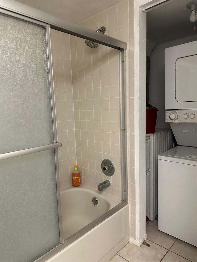 bathroom featuring shower / bath combination with glass door, stacked washer and dryer, and tile patterned flooring