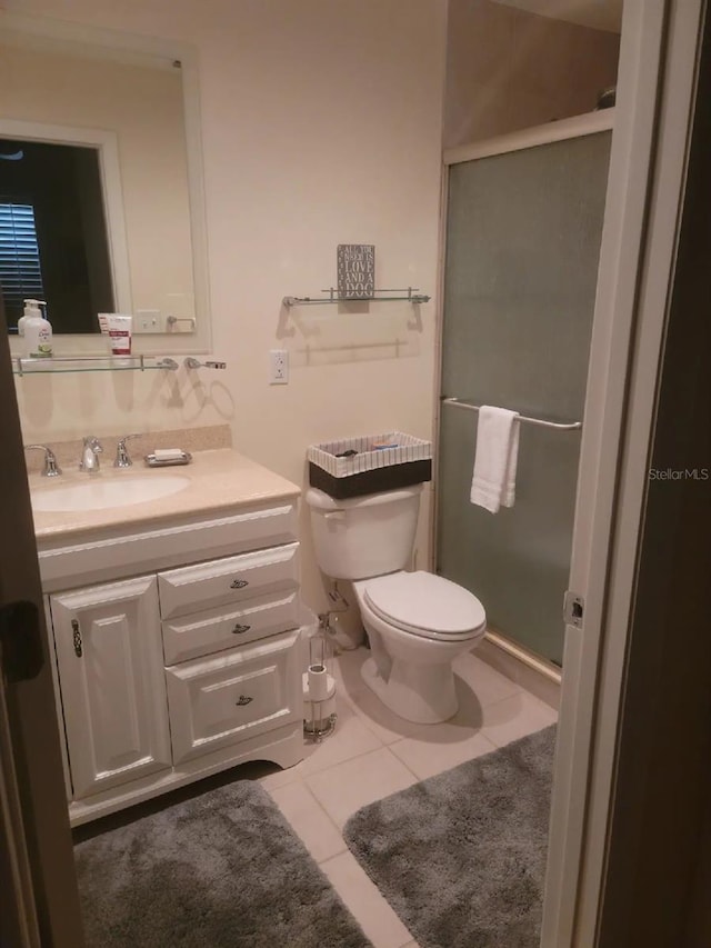 bathroom featuring tile patterned floors, vanity, a shower with door, and toilet