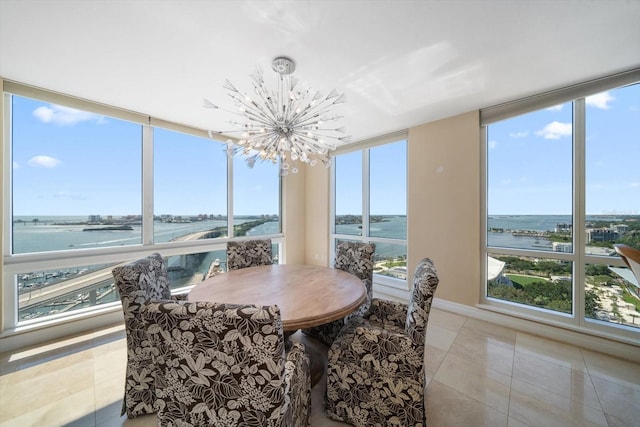 sunroom / solarium featuring a water view and a notable chandelier