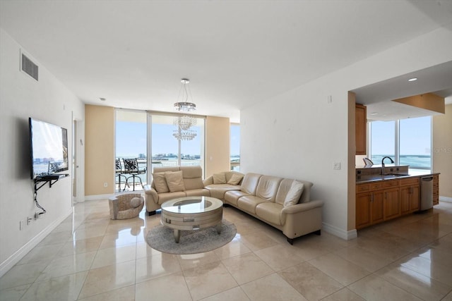 living room with a notable chandelier, a water view, sink, light tile patterned floors, and floor to ceiling windows