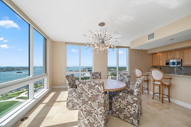 dining space with a chandelier, a water view, visible vents, and baseboards