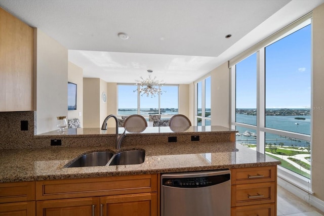 kitchen featuring light stone counters, a notable chandelier, a water view, a sink, and dishwasher