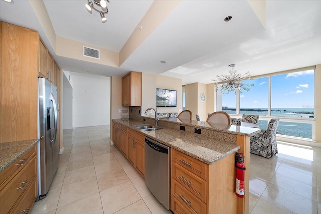 kitchen with a breakfast bar, stainless steel appliances, a water view, visible vents, and a sink