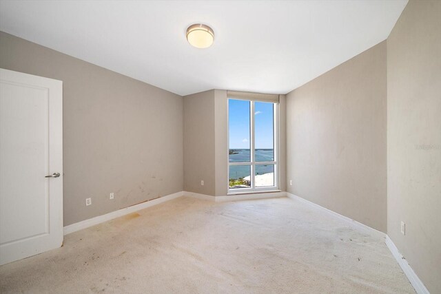 carpeted empty room featuring a water view