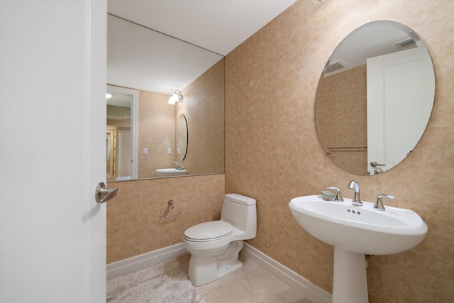 half bath with toilet, tile patterned flooring, visible vents, and baseboards