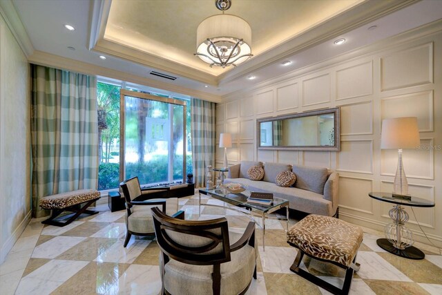 living room with crown molding, a tray ceiling, a notable chandelier, and a wealth of natural light